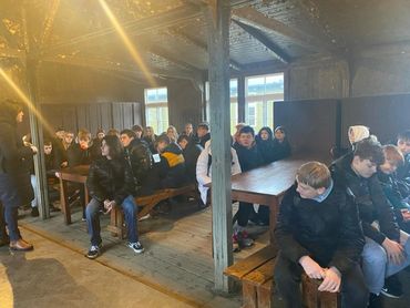 Group of students sitting on benches listening to a speaker, Berlin trip