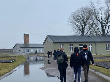 Students walking toward green buildings at a camp-style site, Berlin trip
