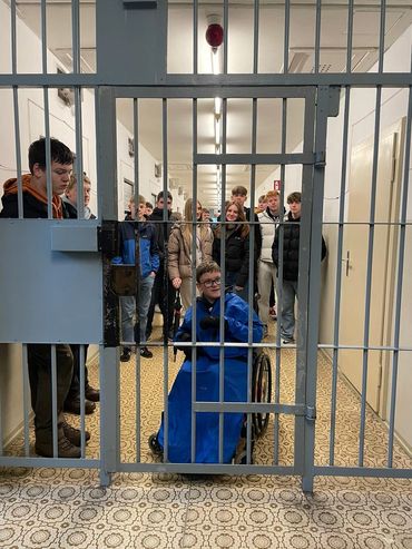 Students behind a metal gate in a prison cell corridor, Berlin trip