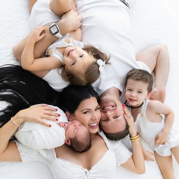Happy family of 5 laying down on bed.