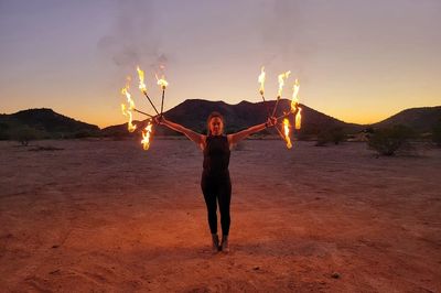 Person performing fire dancing at sunset in a desert.