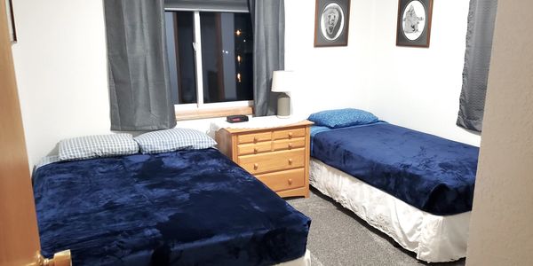 A small bedroom with two beds and blue blankets.