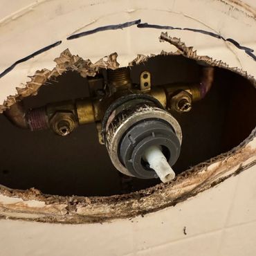 Exposed shower valve with the handle missing, leaving a hole in the wall that can cause leaks, water