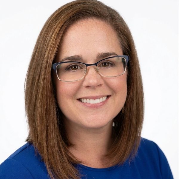 Smiling woman with glasses and brown hair.