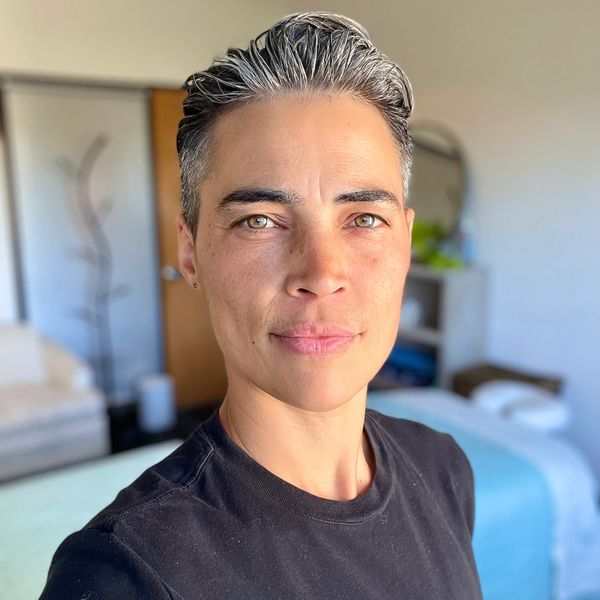 Confident person with short salt-and-pepper hair in a cozy room.