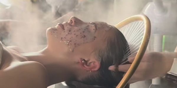 Person receiving a head spa and facial steam treatment in a head spa.