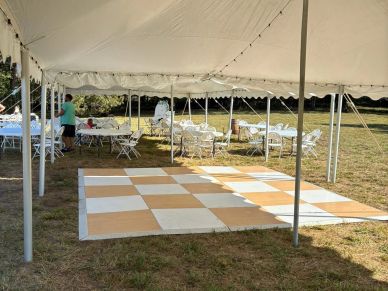 Empty outdoor event tent with chairs and checkered floor.
