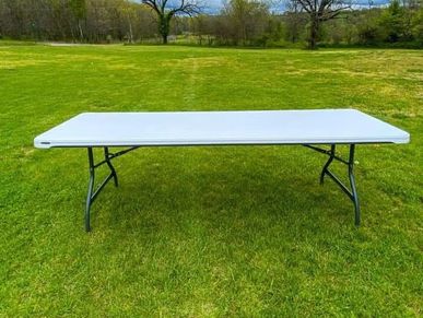 White folding table on green grass.