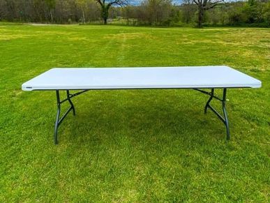 White folding table on green grass.