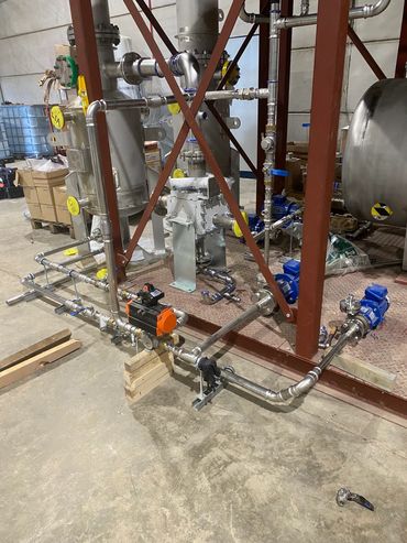 Industrial piping system with valves and pumps in a warehouse.