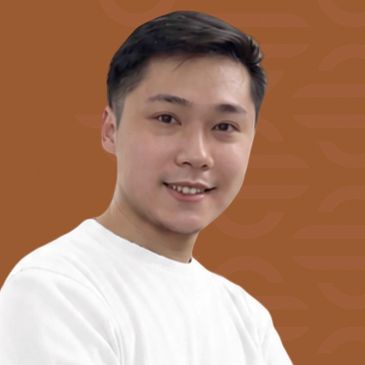 Young man smiling in a white shirt against a brown background.