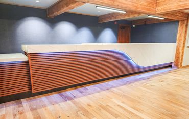 Modern reception desk with wood paneling and blue LED lighting.