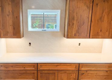 Wooden kitchen cabinets with a clean white countertop and small window.