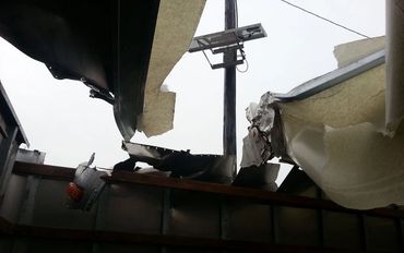 An Electric Pole Visible From a Broken Container Roof