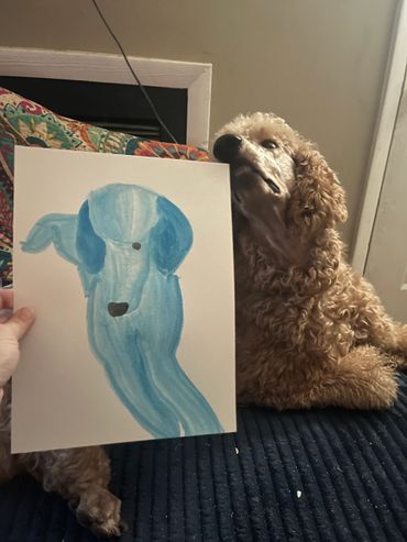 Curly dog next to a blue dog painting.