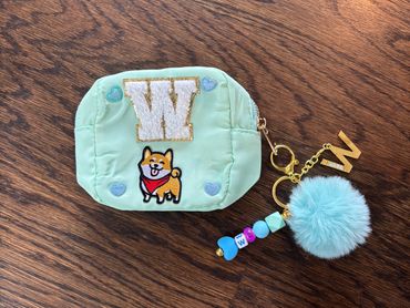 Mint green pouch with cute patch and blue pom-pom keychain.