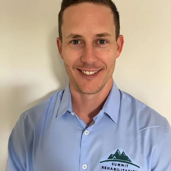 Smiling man in a blue Summit Rehabilitation shirt.