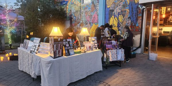 Outdoor night market stalls with illuminated lamps and colorful mural.