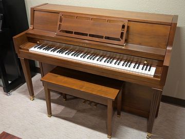 A brown Kawai console piano.