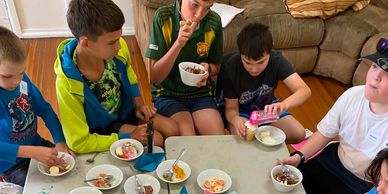 Children enjoying ice cream sundaes together at a table indoors.