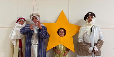 Four children dressed in festive costumes, one as a star.