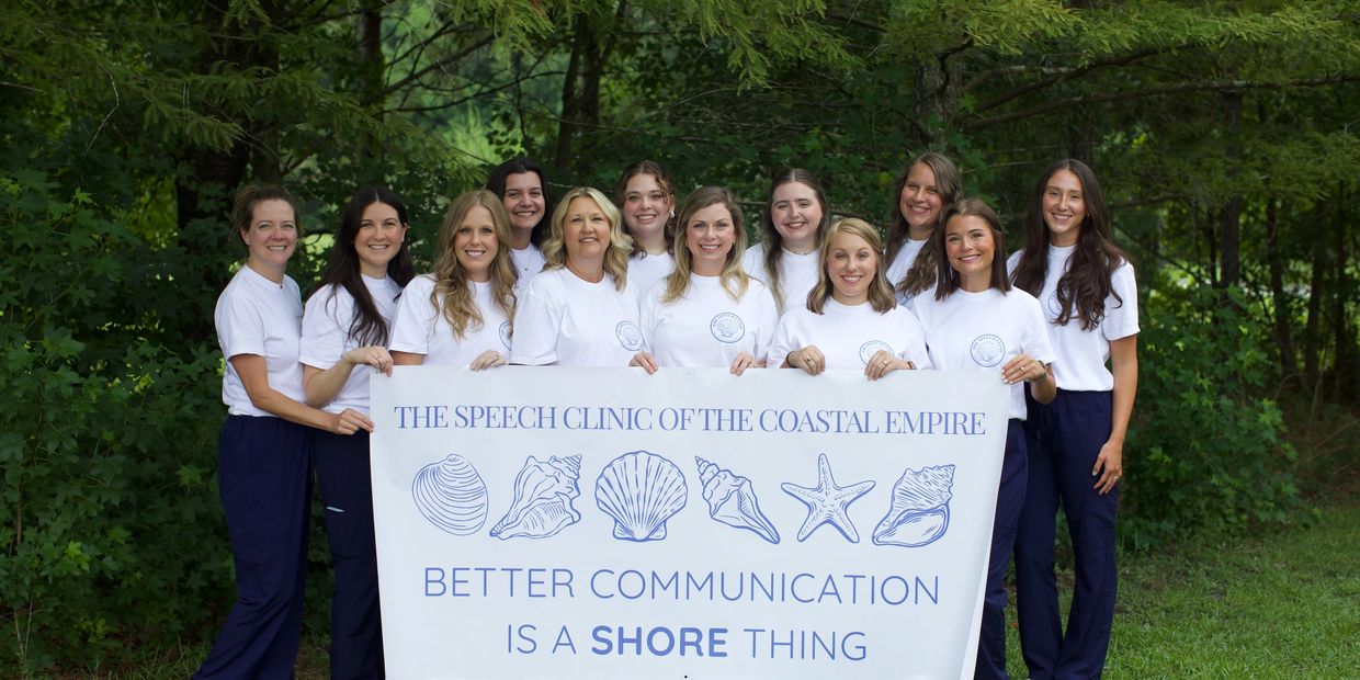 Team holding a sign for The Speech Clinic of the Coastal Empire.