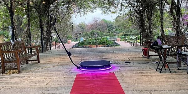 Robotic vacuum cleaning a red carpet in a garden area.