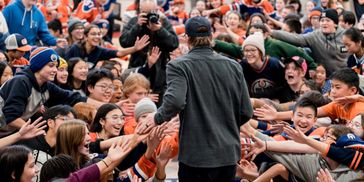 Athlete high-fiving excited fans in a crowded sports event.