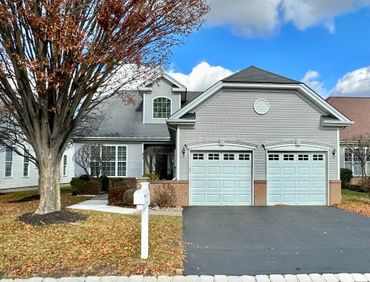 Suburban house with two-car garage and autumn tree in front yard.