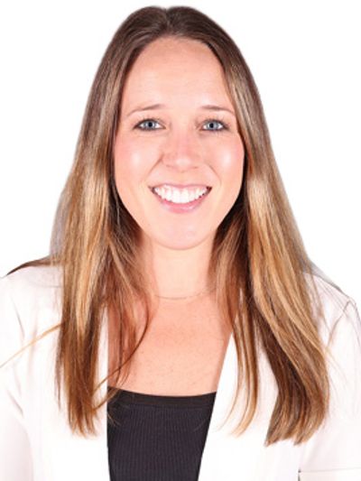 Smiling woman with long hair wearing a white blazer and black top.