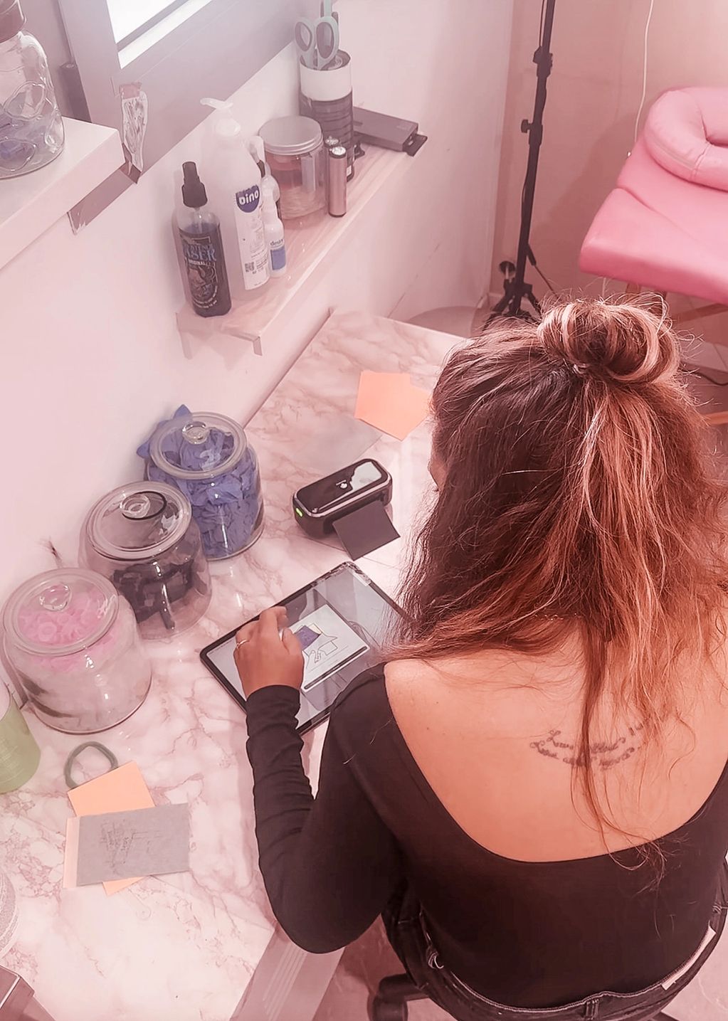 Mujer trabajando en una tablet en una mesa con frascos.