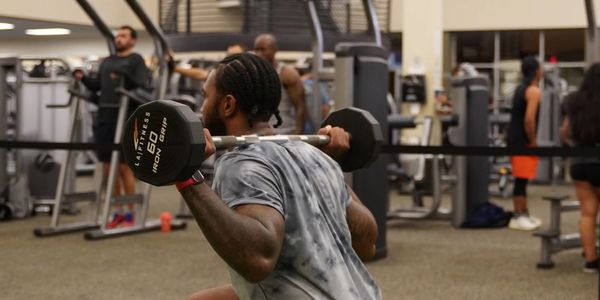 Man doing weighted squats in a gym.