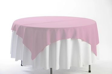 Round table covered with white and pink tablecloths.