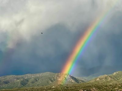 Rainbow coming down over the mountains, blue cloudy sky