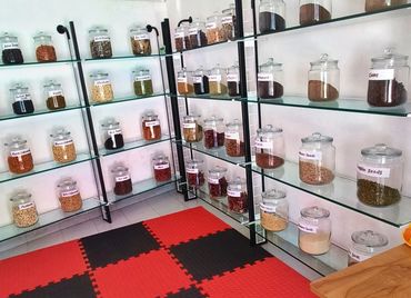 A neatly arranged spice and nut storage area with labeled jars on glass shelves.