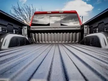 View of an empty truck bed with a red cabin under a blue sky.