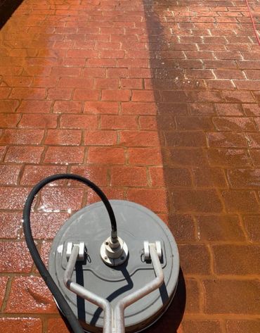 Pressure washing a brick patio, showing clean and dirty sections.