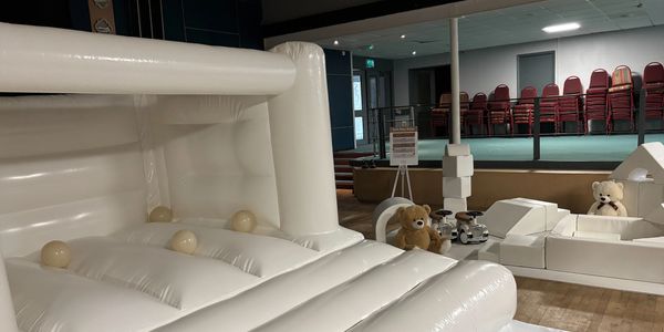 Indoor soft play area with white inflatable structures and teddy bears.