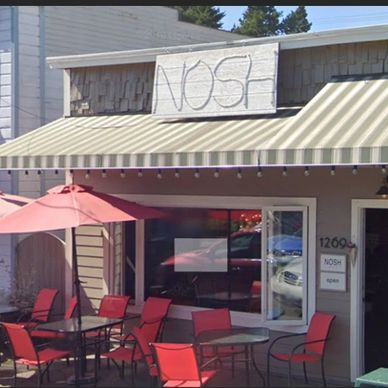 A table with an umbrella and chairs in front of a restaurant.