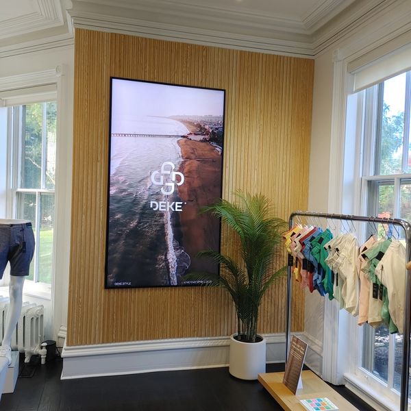Modern clothing store interior with beach-themed digital display and colorful shorts.