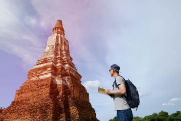 Young man exploring an ancient temple with a map on a sunny day.