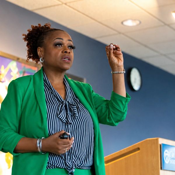 Woman in green suit giving a presentation in a conference room.