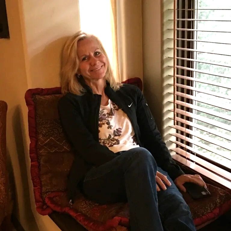 Woman sitting by the window smiling.