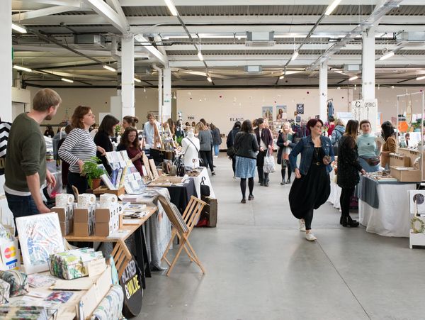 A fair event with lots of people and tables with handmade items