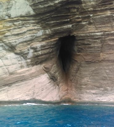 Sea cave entrance in layered rock formation.