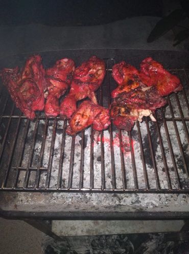Meat grilling on a barbecue grill with glowing coals.