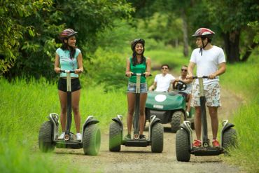 Three people riding segways on a dirt path.