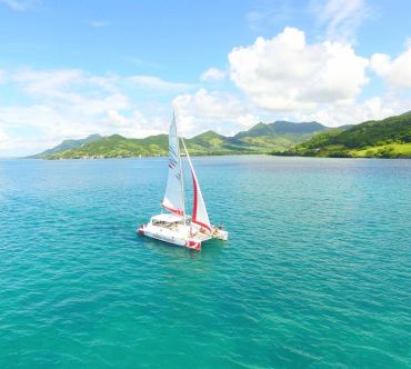 Sailboat on clear blue waters near green mountains