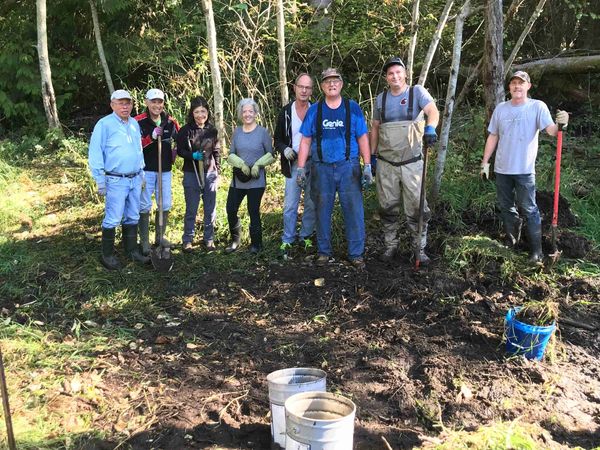 8 volunteers in wet & wooded area with tools and buckets
