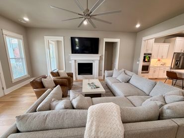 Modern living room with fireplace, TV, leather chairs, and gray sectional sofa.